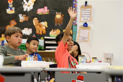 Howard Elementary students sitting at desks and one raising his hand